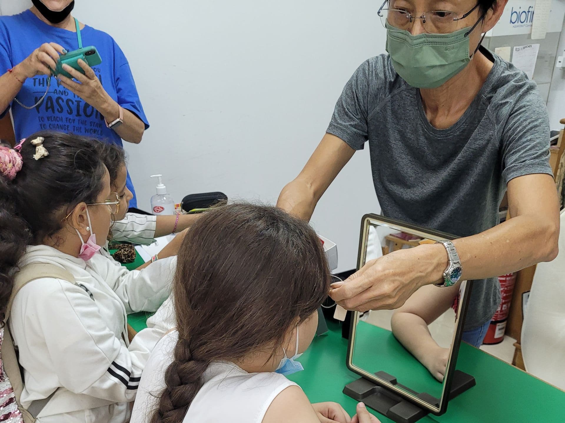 A health worker examining a student’s eyes with a handheld instrument during a school screening.